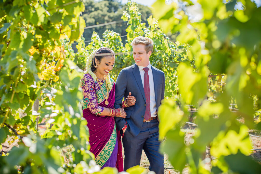 Couple walking through vineyard at Bay Area wedding venue during luxury Indian fusion wedding planned in Northern California